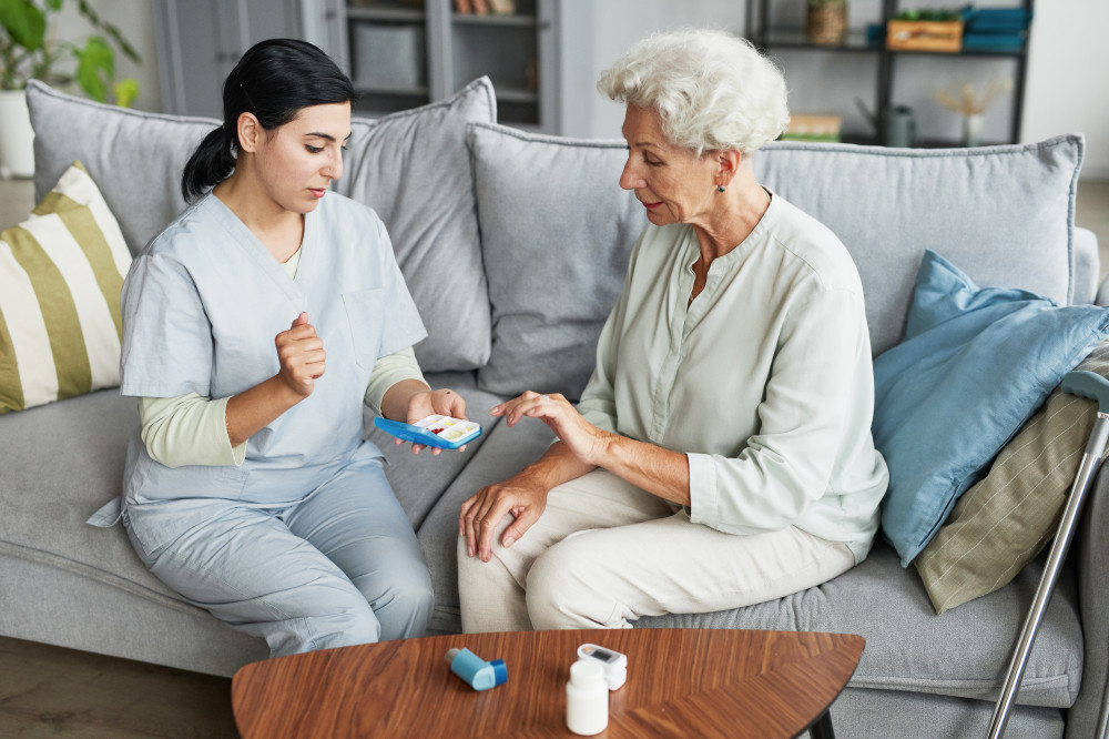 Unterstützung bei der Medikamenteneinnahme zu Hause Pflegekraft unterstützt eine Seniorin bei der richtigen Einnahme ihrer Medikamente